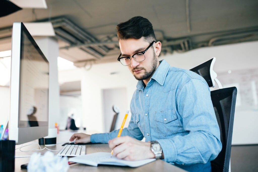 Philotech team member reviewing notes at his desk in a bright office